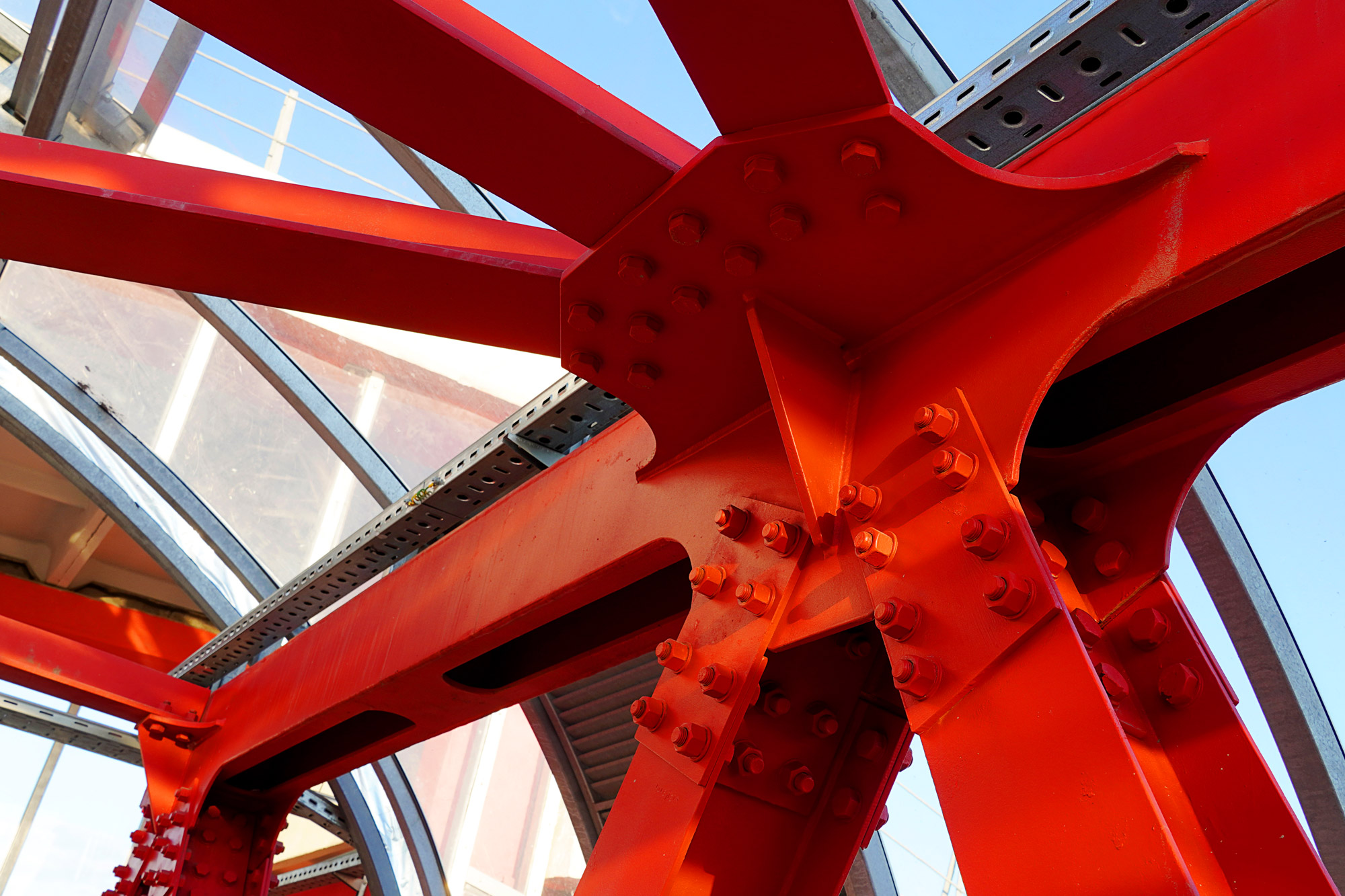 Close-up of industrial red epoxy coating on structural steel connection beams and bolts
