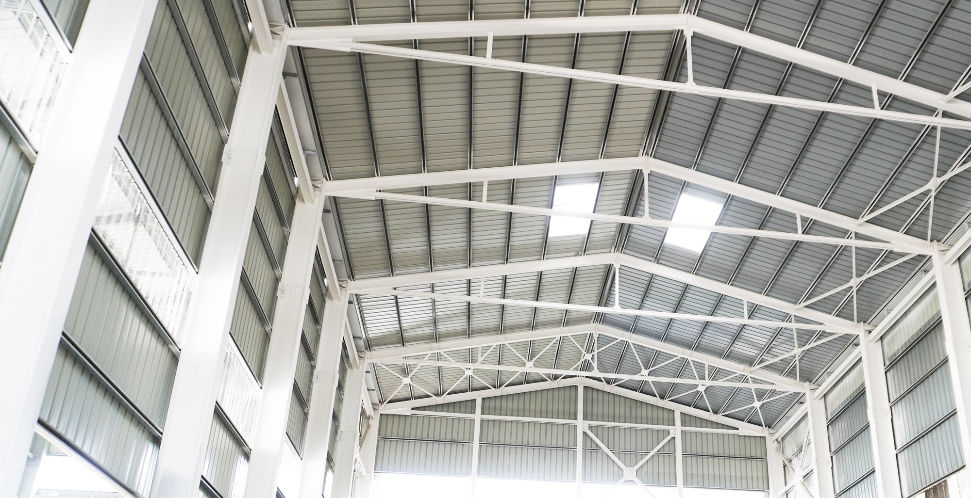 Freshly painted structural steel beams inside a large industrial facility with white protective coating